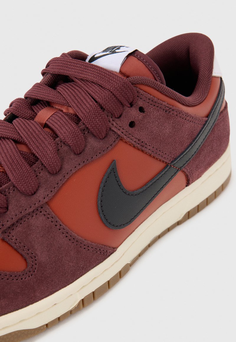 Baskets Nike bordeaux en mélange de matières en daim et en cuir, avec un swoosh noir et une semelle en caoutchouc à grip texturé.