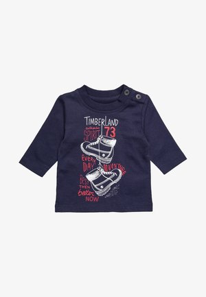 Chemise à manches longues bleu marine avec un graphisme de bottes accompagné des textes : « Timberland authentic spirit 73 », « every day adventure » et « better now ».