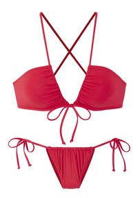 Červený bikiny set, ktorý obsahuje zvršok s prekríženými tenkými pásikmi a nastaviteľnými šnúrkami, spolu so zodpovedajúcimi spodkami so šnúrkami na bokoch.