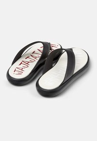 Black flip-flops with wide straps, a cushioned white sole featuring red and white text, and a smooth, glossy finish.