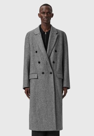 Palton gri cu lungime dublă, din țesătură herringbone, cu rever tăiat, buzunare frontale și nasturi negri. Material din amestec de lână cu o textură netedă.