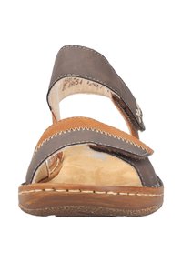 Brown leather sandal with adjustable straps, a lighter brown insole, and stitched detailing along the edges. Flat sole with a textured finish.