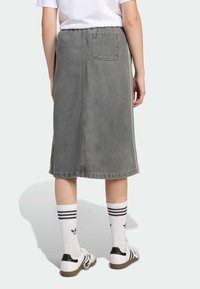 Grå denim midi skjørt med elastisk linning, baklomme og dekorative sømmer. Brukt med hvite sokker med svarte striper og mønster.