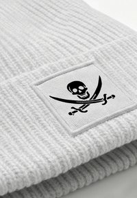 Gray knitted beanie with a ribbed texture and a square patch featuring a black skull and crossbones design.