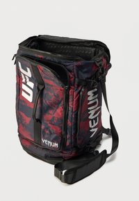 Κόκκινο και ναυτικό σακίδιο με πολλαπλές θήκες με φερμουάρ, μαλακό λουράκι ώμου και έντονα λευκά λογότυπα UFC και VENUM. Υφασμάτινη υφή.