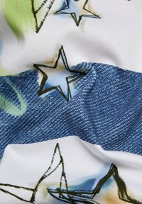 Baumwollstoff mit einer Denim-Struktur und einem bunten Sternmuster in Blau und Grün auf einem weißen Hintergrund. Faltenstruktur sichtbar.