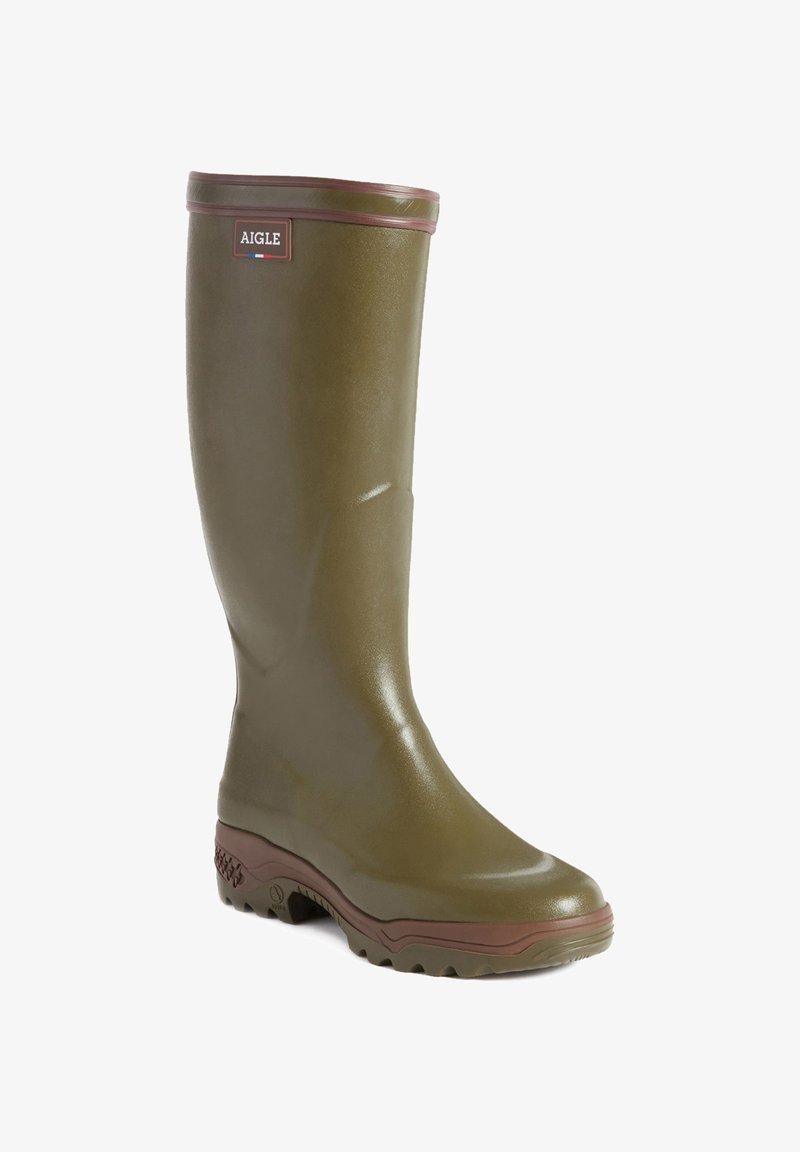 Green rubber knee-high boot with brown accents, textured finish, and a chunky sole. Features a logo badge near the top. Round toe design.