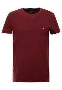 Camiseta roja de algodón con mangas cortas, cuello redondo y un pequeño logo en el pecho. Textura suave y corte clásico.