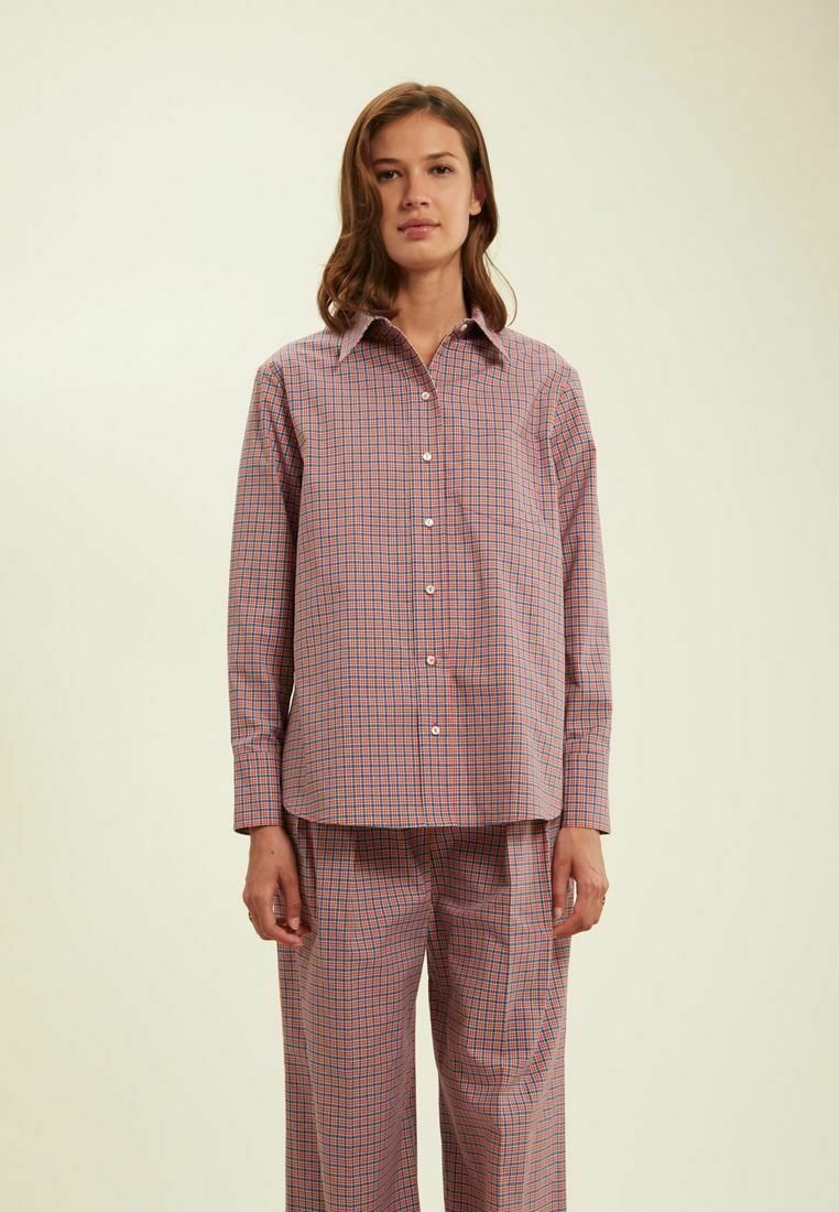 Chemise à carreaux légère rouge, bleue et blanche. Présente un col pointu et des manches longues. Associée à un pantalon à carreaux assorti.