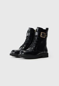 Botine negre din piele, cu vârfuri rotunde, șireturi în partea din față, fermoare pe lateral și o curea cu un detaliu de cataramă în ton cu aurul.