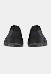 Scarpe sportive nere con tomaia lavorata, dotate di colletto imbottito e inserti riflettenti. Suola spessa con battistrada in gomma per una migliore aderenza.