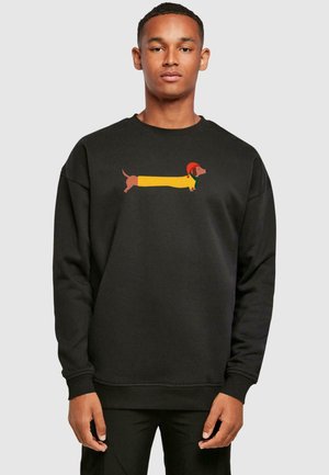 Felpa nera con un grafico di un bassotto in camicia gialla e cappello rosso. Il design è centrato sul davanti.