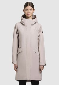 Parka imperméable rose clair avec capuche, dotée de deux poches avant, d'une coupe droite et d'une texture lisse. Marque discrète sur la poitrine.