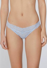 String en dentelle bleu clair avec motif floral, bords festonnés et texture douce, conçu pour le confort et le style.