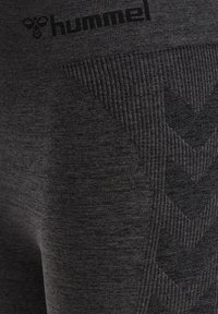 Svarta atletiska leggings med texturerade detaljer, med ett ribbat mönster och ett zickzackmönster. Logotyp tryckt nära midjan.