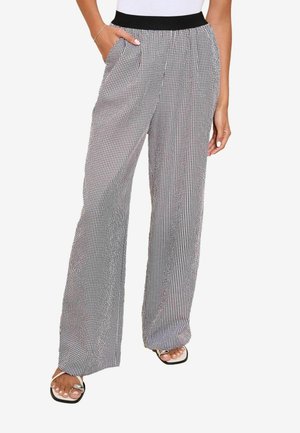Pantaloni a gamba larga a scacchi bianchi e neri con elastico in vita nera e tasche laterali. Tessuto leggero con una consistenza liscia.
