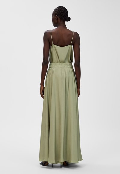 Maxikleid in hellem Olivgrün, mit dünnen Trägern, einer taillierten Taille und einem fließenden Rock. Sanfter Stoff mit weicher Textur.