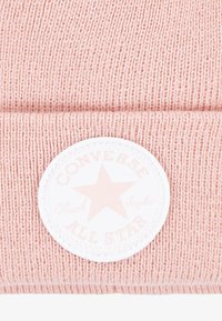 Rózsaszín kötött sapka hajtott széllel, fehér kör alakú folttal, amelyen csillag és a dombornyomott "Converse All Star" logó található.