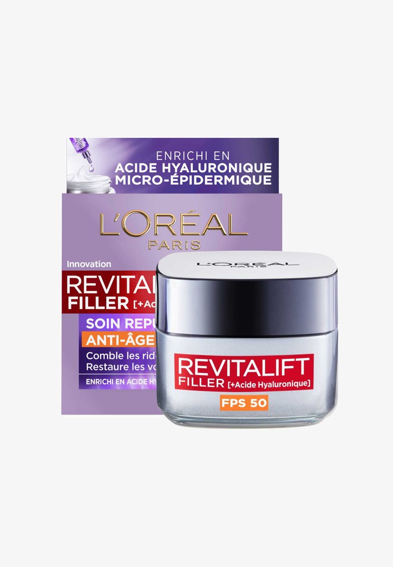 Un pot de crème Revitalift Filler avec un emballage argenté et violet; comprend une étiquette "FPS 50", présentant une texture lisse et brillante et un design arrondi.