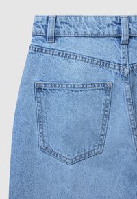Jeans in denim blu chiaro con tasca posteriore curva e cuciture a contrasto. Il tessuto ha una texture liscia con modelli di trama visibili.