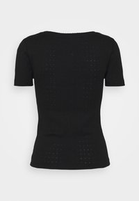 Haut en maille noir à manches courtes et ajusté, avec un motif perforé subtil et un col rond, vu de dos sur fond blanc.