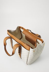 Sac fourre-tout en tissu crème avec un motif géométrique, anses en cuir marron et une fermeture éclair dorée à l'intérieur. Comprend deux compartiments.