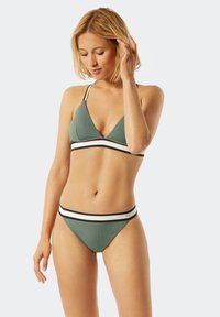 Olivgrünes Bikini mit einem dreieckigen Oberteil und tief sitzenden Hosen, das weiße und schwarze horizontale Streifen entlang des Bands zeigt. Glatte Textur.
