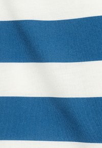 Bomullstyg med växelvis marinblå och vita ränder. Texturen verkar slät med en subtil glans. Ränderna är jämnt fördelade.