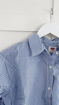 Blue and white striped shirt with small white dots, button-up front, fold-down collar, displayed on a hanger. Cotton material.