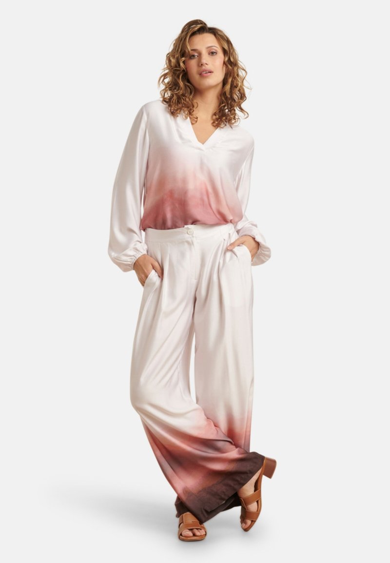 Satinbluse mit V-Ausschnitt und langen Ärmeln, mit einem Ombre-Effekt, der von Weiß zu Pink übergeht. Weite Hose im passenden Stil.