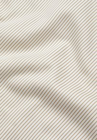 Bomullsstoff med fine, jevnt fordelte gullstriper på en off-white bakgrunn, som viser en glatt tekstur og liten glans.