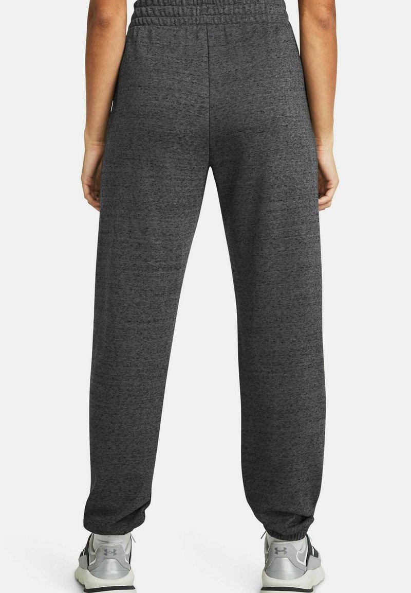 Graue Sporthose mit weicher Textur, elastischem Bund und schmal zulaufenden Bündchen, kombiniert mit hellgrauen Sneakers.