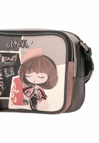 Borsa a tracolla realizzata in un materiale morbido e testurizzato. La palette di colori include rosa, crema e marrone con un design cartoon, accenti luccicanti e dettagli ricamati.