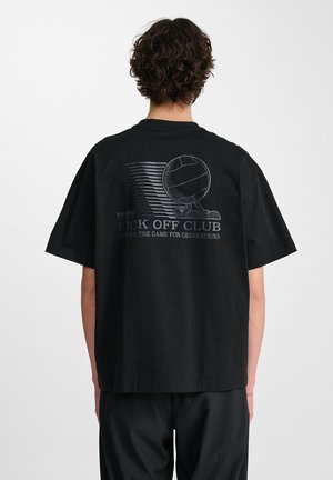 Čierne bavlnené tričko s voľným strihom. Na zadnej strane obsahuje grafický dizajn s motifom volejbalu a bielym textom.