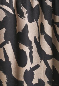 Tela negra y beige con un patrón texturizado de trazos de pincel audaces que asemejan formas abstractas. Material suave y con caída.