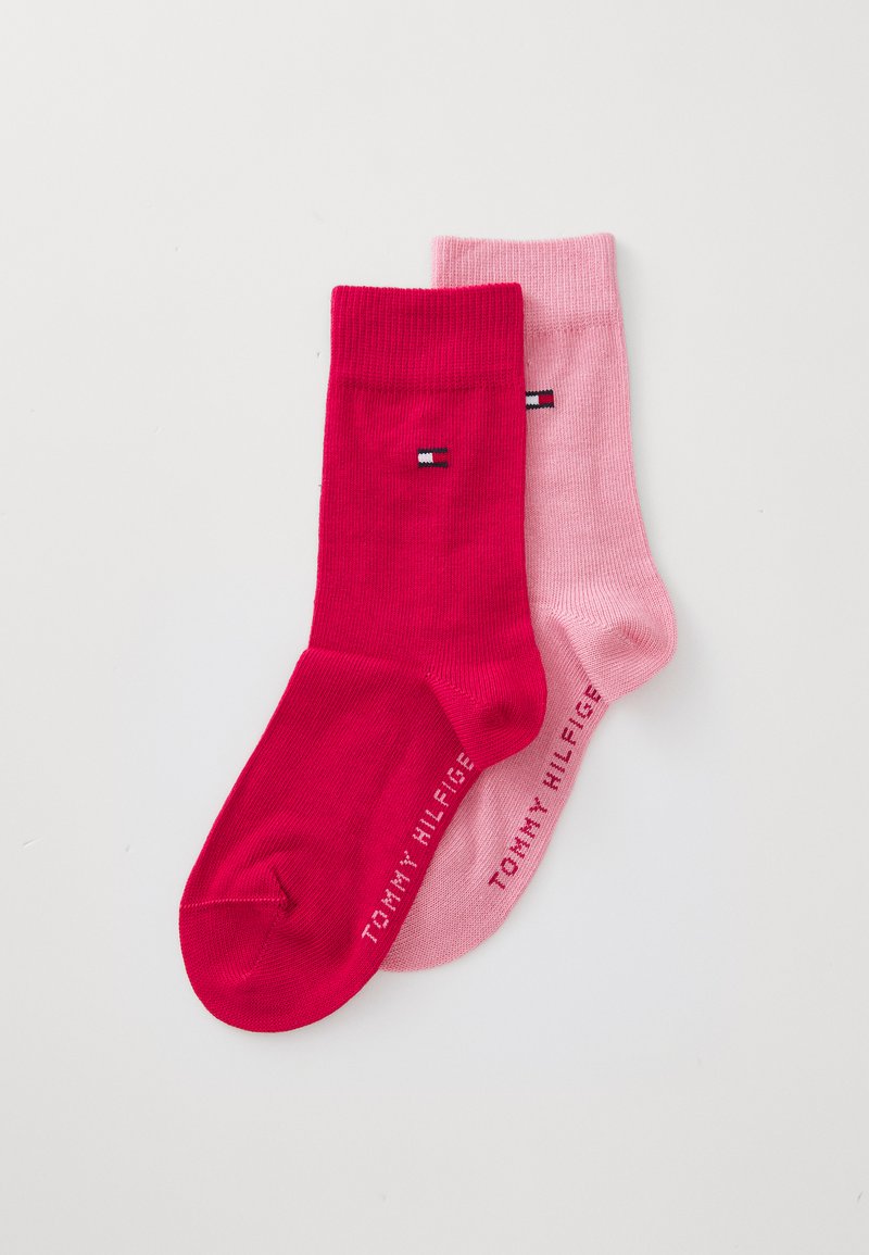 To par sokker: én i knallrosa og den andre i en lysere rosa. Hver har en stripete tekstur med en liten logo på siden.