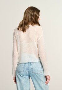 Maglione leggero lavorato a maglia con effetto ombré, che passa da un rosa tenue al bianco; presenta maniche lunghe e un orlo corto.
