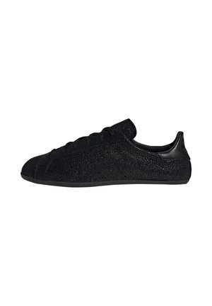 Zwarte lage sneaker met een gestructureerd oppervlak, vetersluiting en glad hielstuk, getoond in zijaanzicht op een witte achtergrond.