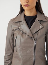 Veste de motard en cuir gris avec un col cranté, une fermeture éclair asymétrique à l'avant et une poche latérale. Texture lisse avec des détails de couture subtils.