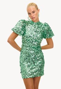 Vestido verde de lentejuelas con una silueta ajustada, mangas cortas abullonadas, cuello alto y una textura brillante. Los detalles decorativos realzan el diseño.