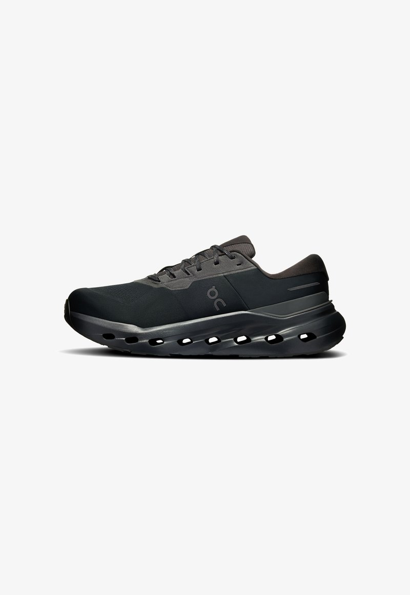 Chaussure de sport noire à tige basse avec fermeture à lacets, col rembourré et semelle ventilée comportant plusieurs découpes ovales.