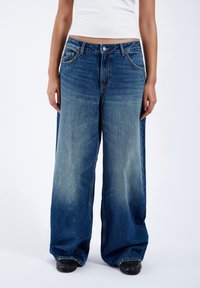 Wide-leg denim jeans in a faded dark blue wash, featuring a five-pocket design, button closure, and subtle fading along the thighs.