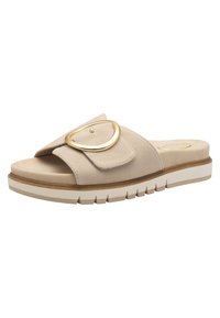 Beige suede slide sandal with wide strap, large gold oval buckle, cushioned footbed, and white rubber sole with tread pattern.