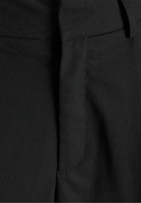 Svarta tygbyxor med en slät textur, som har en framficka och diskret sömdetalj längs kanterna.