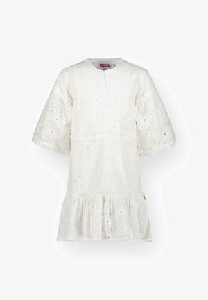 Világoskék farmerdzseki színes foltokkal, fehér horgolt ruhával, amelynek fodros szegélye van, és tengerészkék magasszárú tornacipővel párosítva.