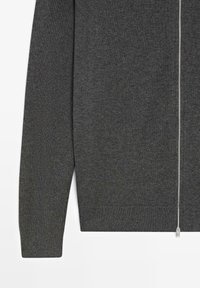 Maglione grigio con cerniera, realizzato in tessuto a maglia a costine. Presenta una zip argentata sul davanti e polsini e orlo a costine.