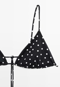 Haut de bikini triangle noir à pois blancs avec fines bretelles ajustables et fermeture à nouer dans le dos.