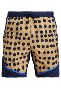 Short beige et bleu marine avec de gros pois noirs, ceinture bleu marine avec cordon, liseré bleu et petit logo Nike à l'avant de la jambe gauche.