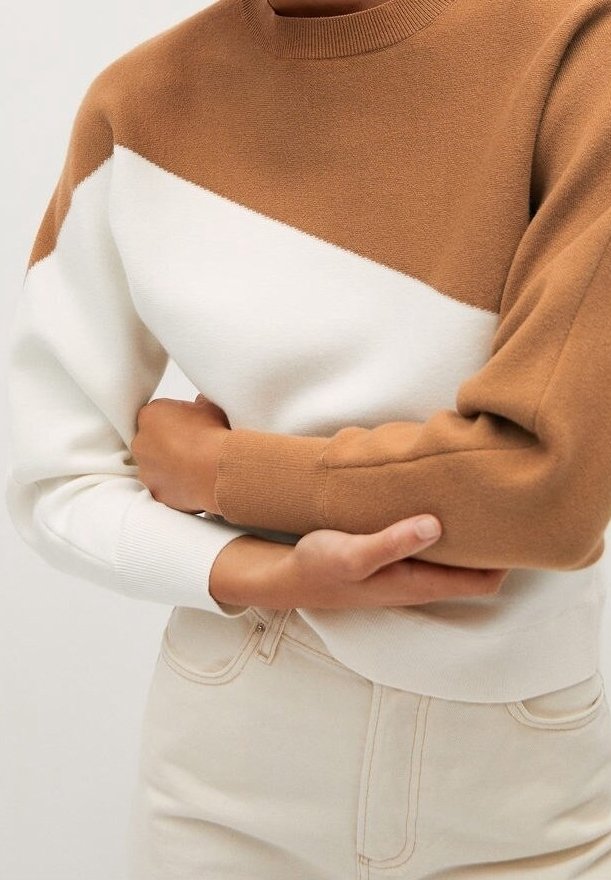 Maglione a blocchi di colore marrone e bianco con scollatura rotonda, polsini a costine e una consistenza morbida; abbinato a pantaloni chiari.