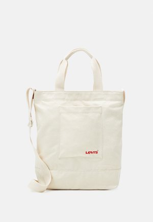 Sac cabas en toile crème avec poche avant et logo Levi's rouge, doté de deux anses et d'une bandoulière ajustable.